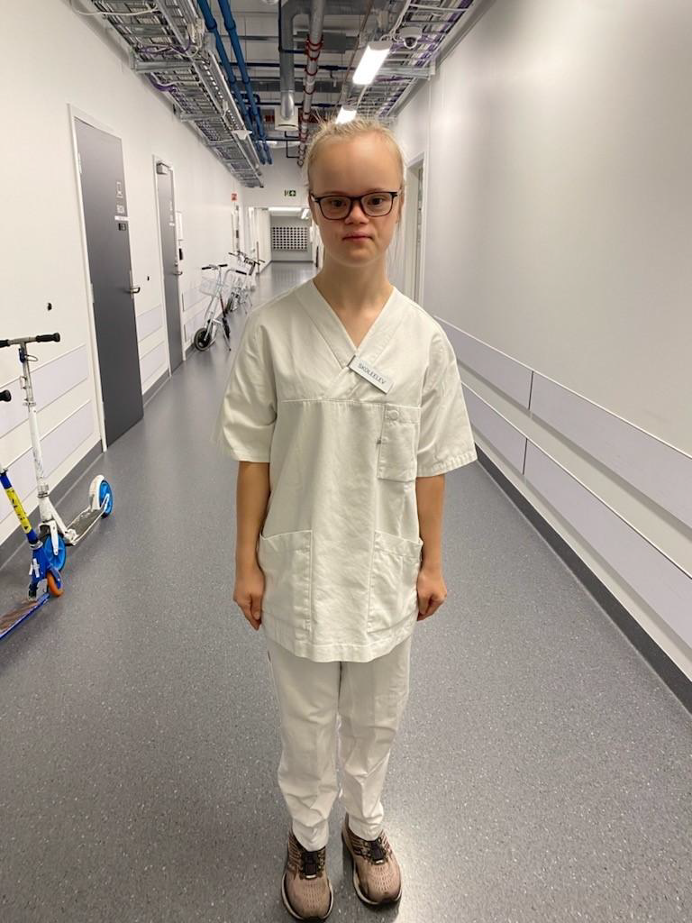 Bilde av en ung voksen dame med Downs syndrom i helsefaglig uniform